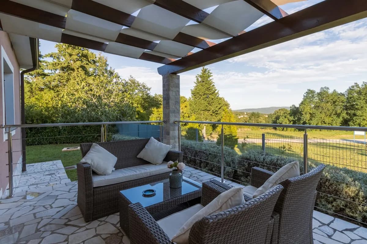 Paved covered terrace with outdoor armchairs
