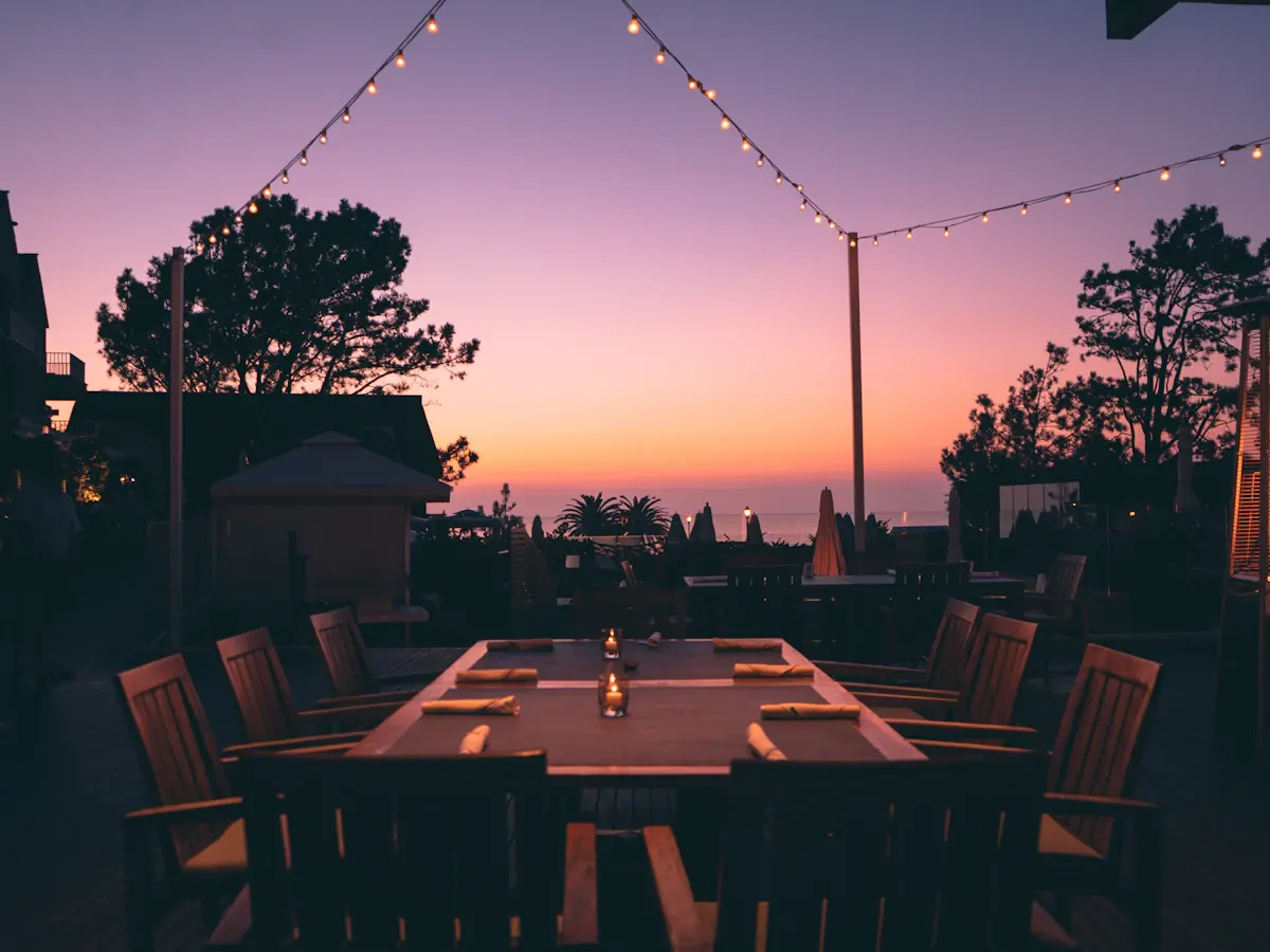 Outdoor dining table beneath string lights at dusk