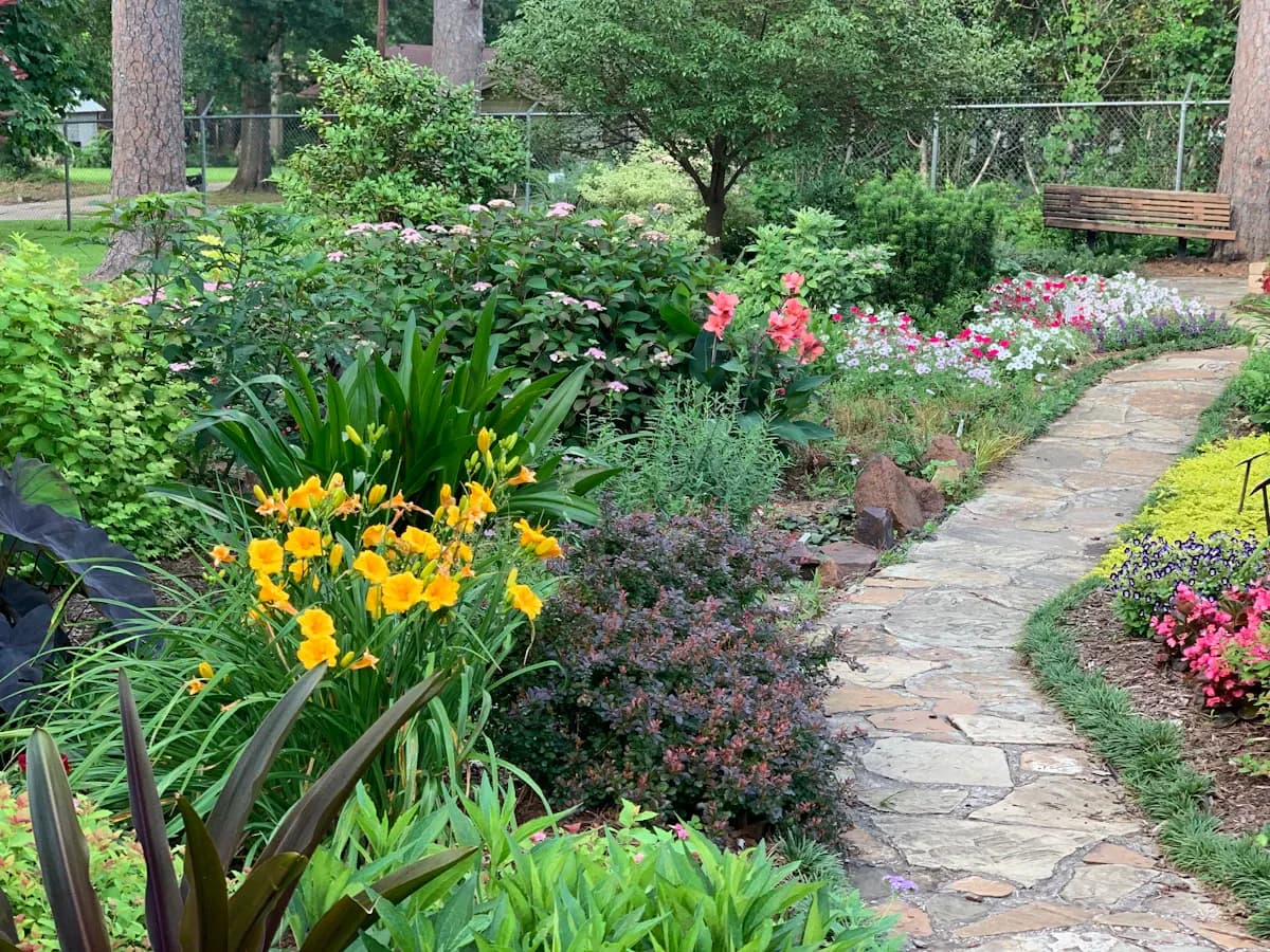 Narrow stone garden path between flowering borders